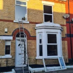 A two-story terrist brick house with white pvc windows. The house has large bay style window on the ground floor